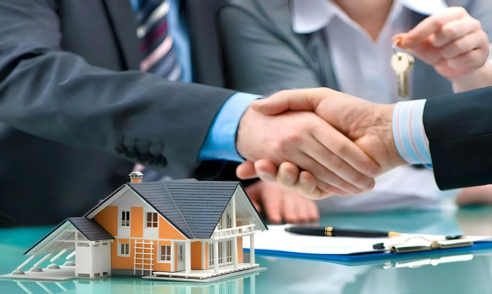 Two people shaking hands over a house model and keys after they verify a real estate agent in Dubai
