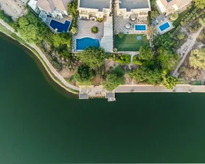 Dubai Hills Estate vs Arabian Ranches: aerial view of villas with private pools beside a lake in Dubai