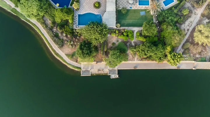 Dubai Hills Estate vs Arabian Ranches: aerial view of villas with private pools beside a lake in Dubai