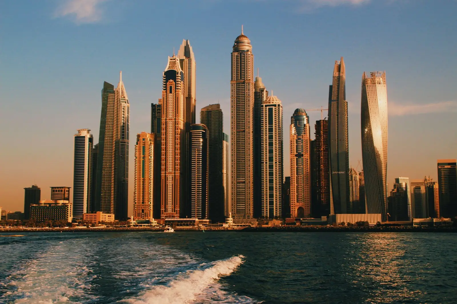 Dubai Marina vs JLT: Dubai Marina towers at sunset seen from the water