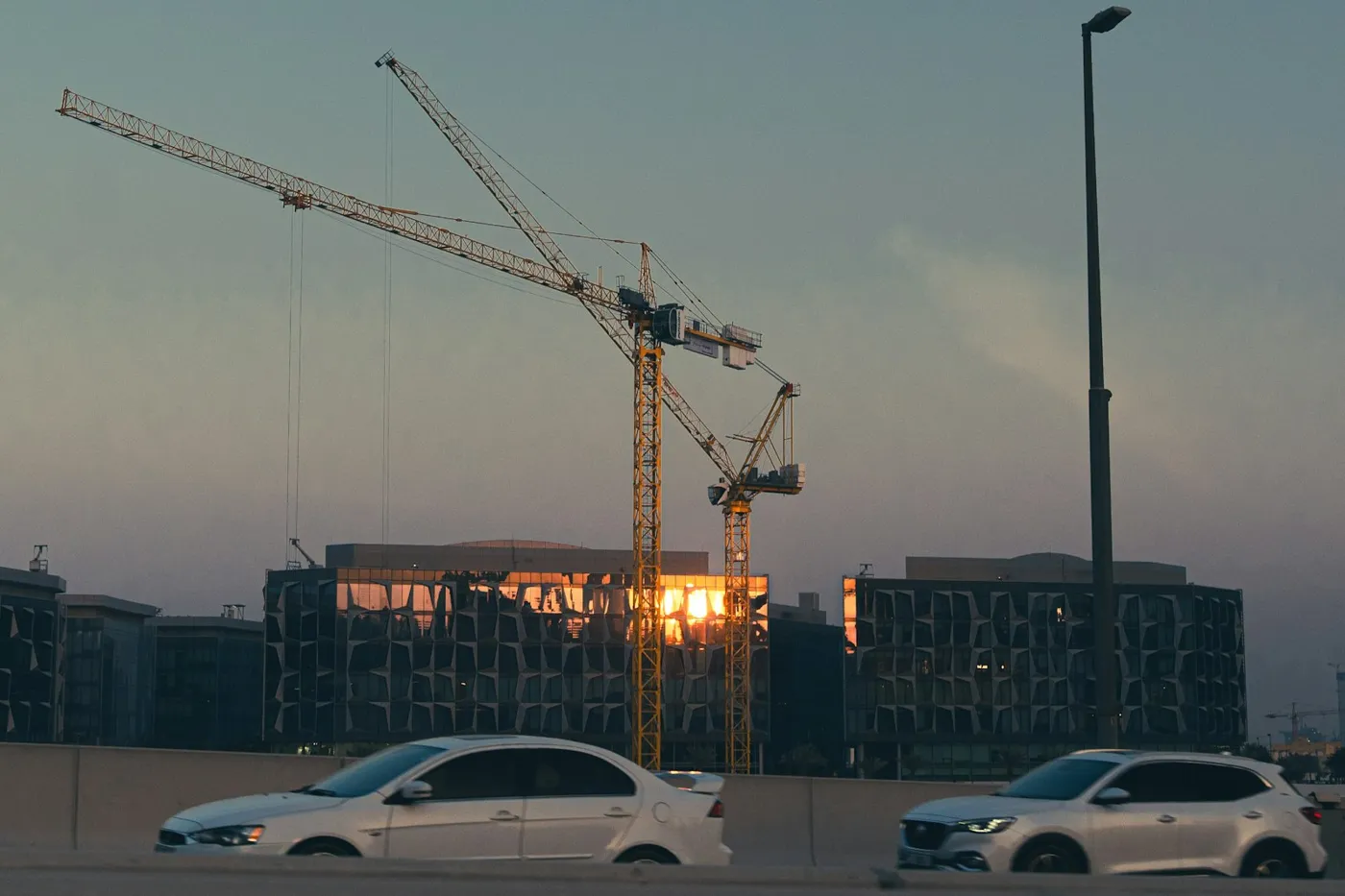 Off-plan resale in Dubai: construction cranes beside towers at sunset