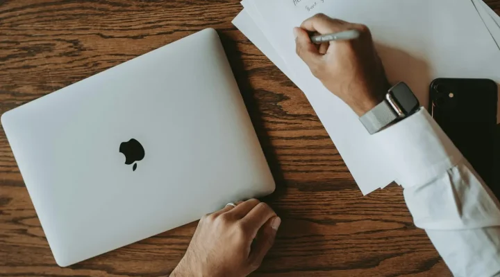 Remote property purchase Dubai: a person signing documents beside a closed laptop