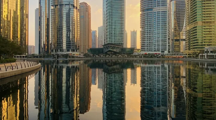 Buying property in JLT: Jumeirah Lakes Towers apartment towers reflected in a lake at sunset