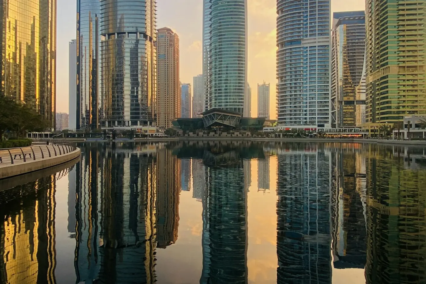 Buying property in JLT: Jumeirah Lakes Towers apartment towers reflected in a lake at sunset